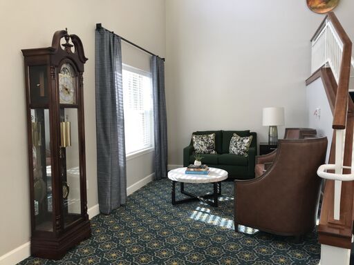 A cozy living room with a grandfather clock and elegant seating arrangement.