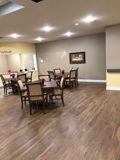 A spacious dining area featuring wooden tables and chairs, illuminated by bright overhead lights.