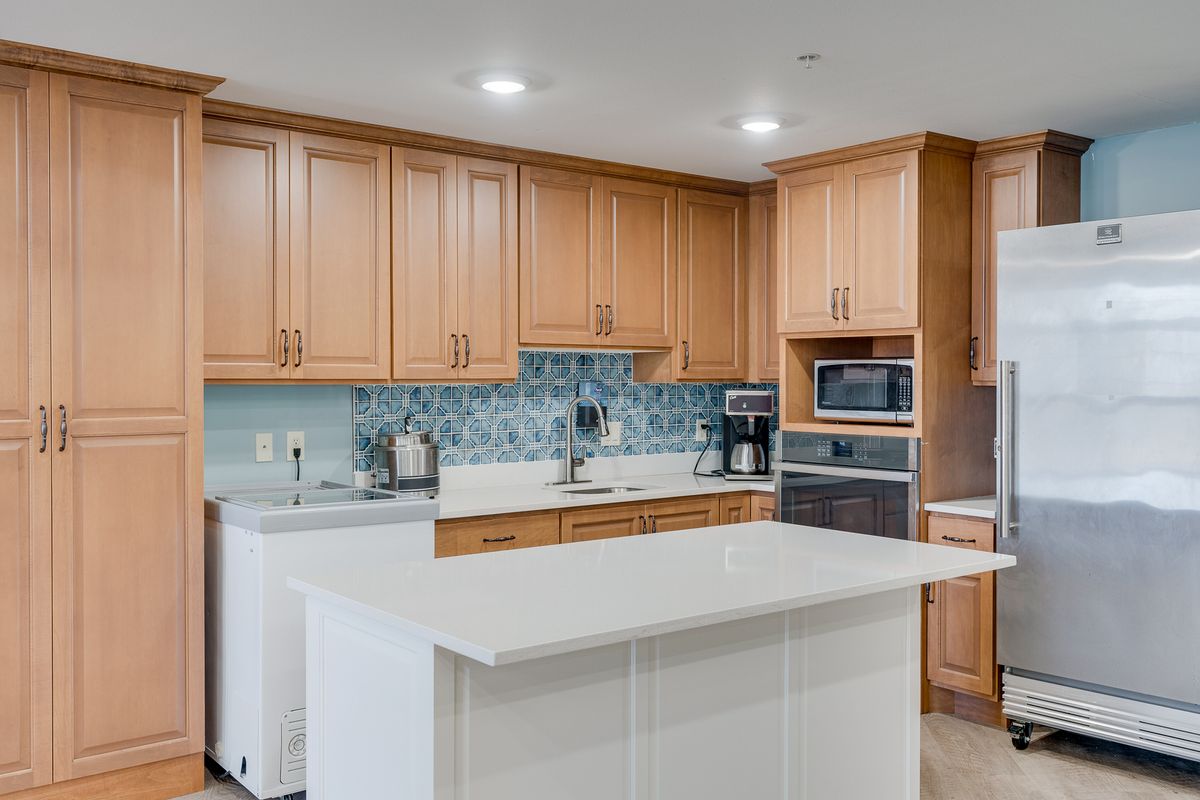 A modern kitchen with wooden cabinets, a central island, and contemporary appliances.