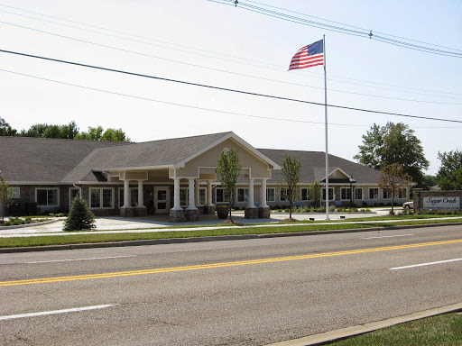 A community center featuring an American flag flying in front, set against a clear blue sky.