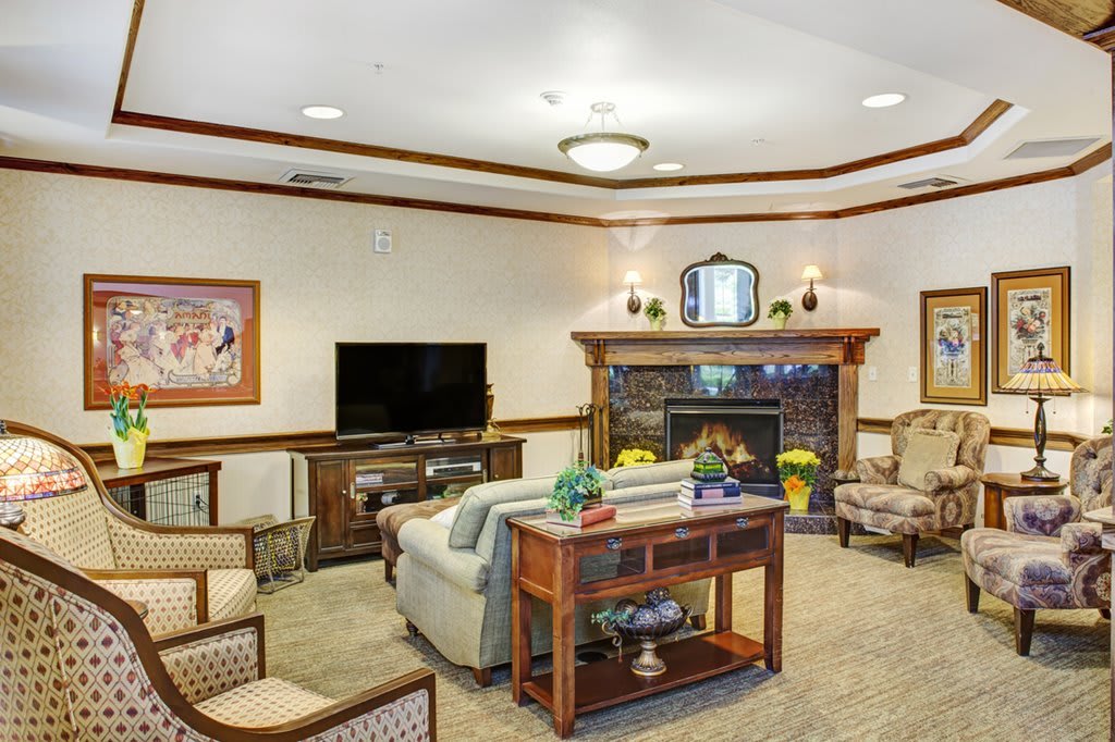 A cozy living room with a fireplace, sofa, armchairs, and a television.