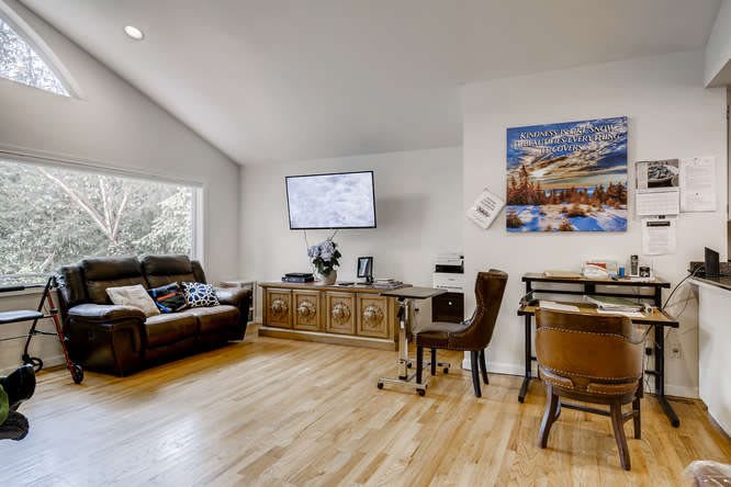 A spacious living room with a comfortable sofa, wooden flooring, and a wall-mounted television.
