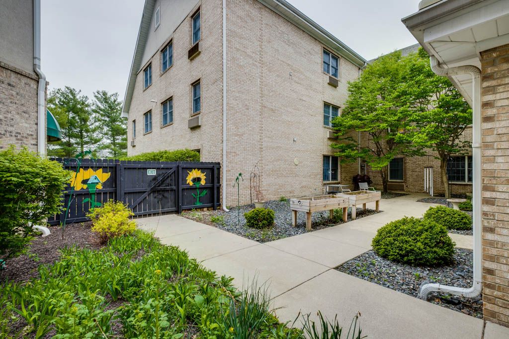 A peaceful outdoor garden area with benches adjacent to a multi-story building.