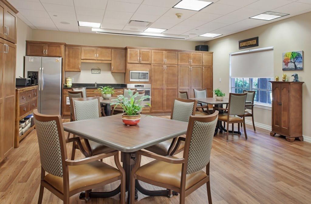 A spacious kitchen and dining area with tables, chairs, and decorative plants.