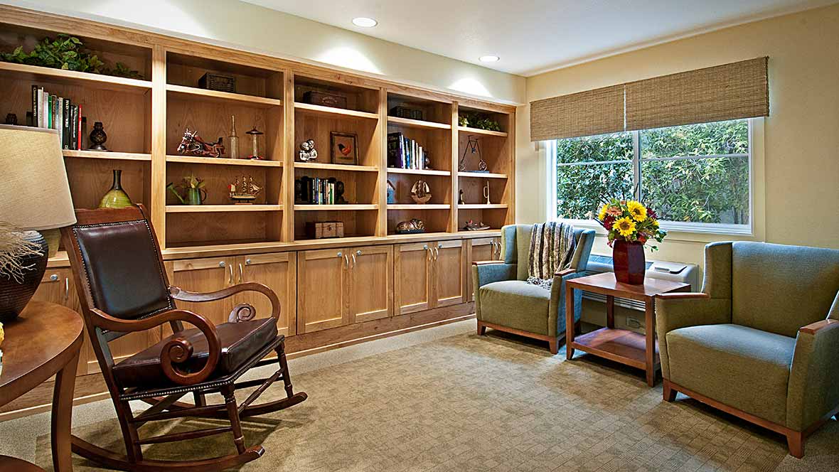 A cozy reading nook with built-in bookshelves, a comfortable armchair, and a bright window.