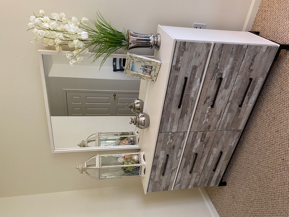 A stylish dresser with a mirror adorned by flowers and decorative items in a beautifully decorated bedroom.