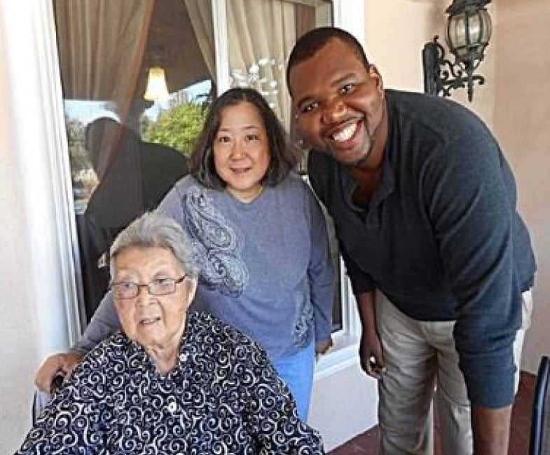 A group of three people, smiling together outdoors.