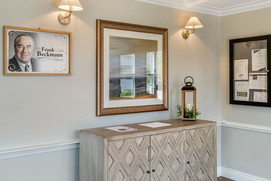 A stylish hallway interior featuring a wooden cabinet, framed artwork, and decorative lamps.