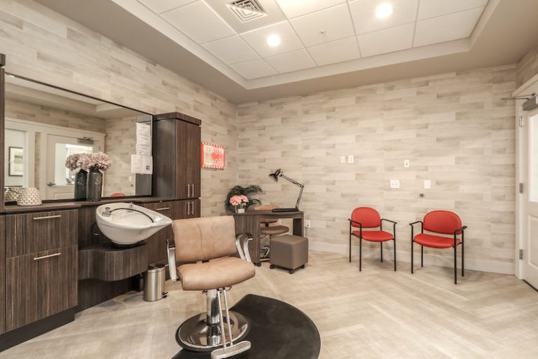 A modern hair salon interior with a styling chair, mirror, and sink, alongside a cozy waiting area.