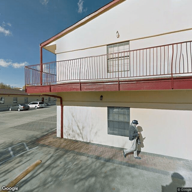 A person walking beside a two-story building with a red balcony.