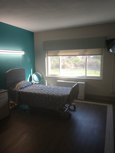 A well-lit hospital room featuring a single bed and a view out the window.