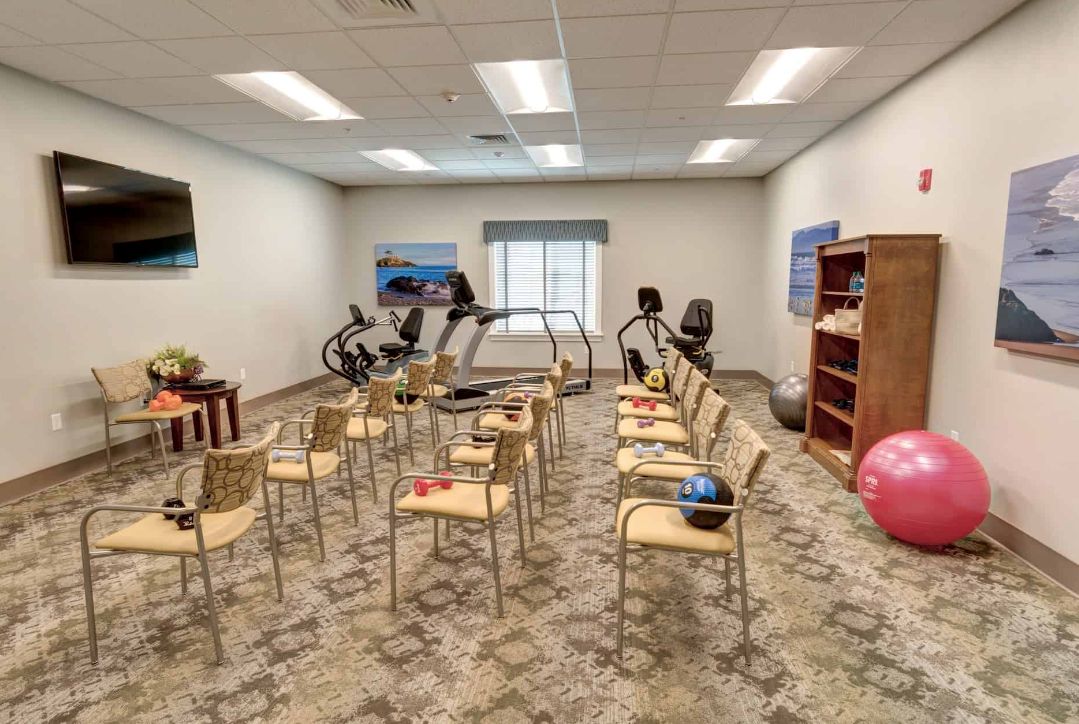 A fitness room equipped with chairs and exercise equipment for therapy sessions.