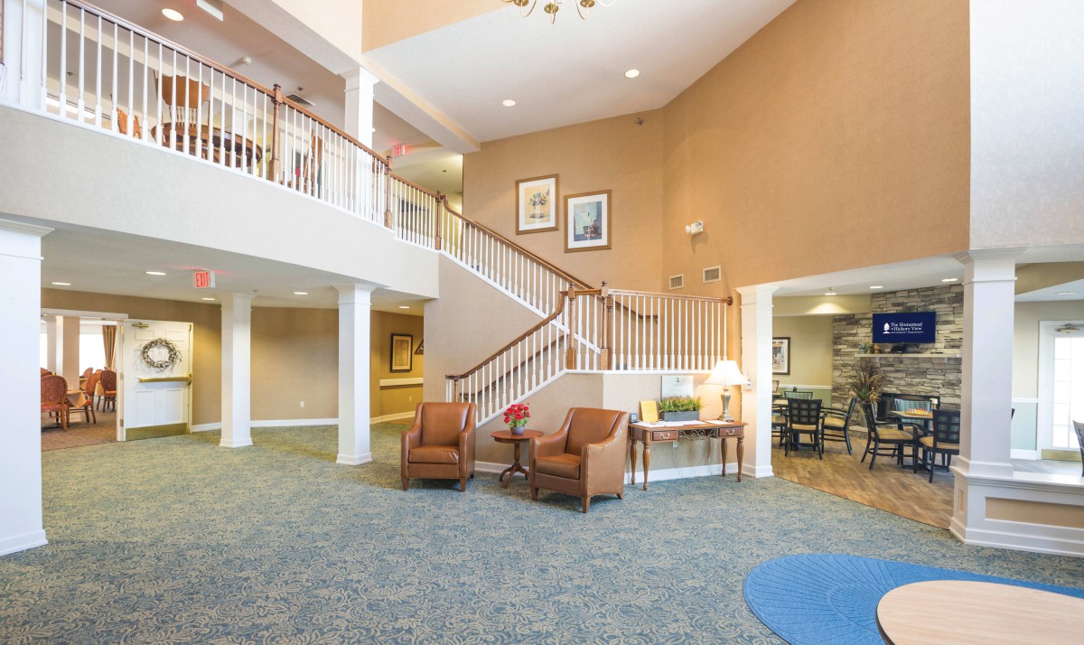 A spacious lobby featuring a seating area with armchairs and a staircase leading to an upper level.