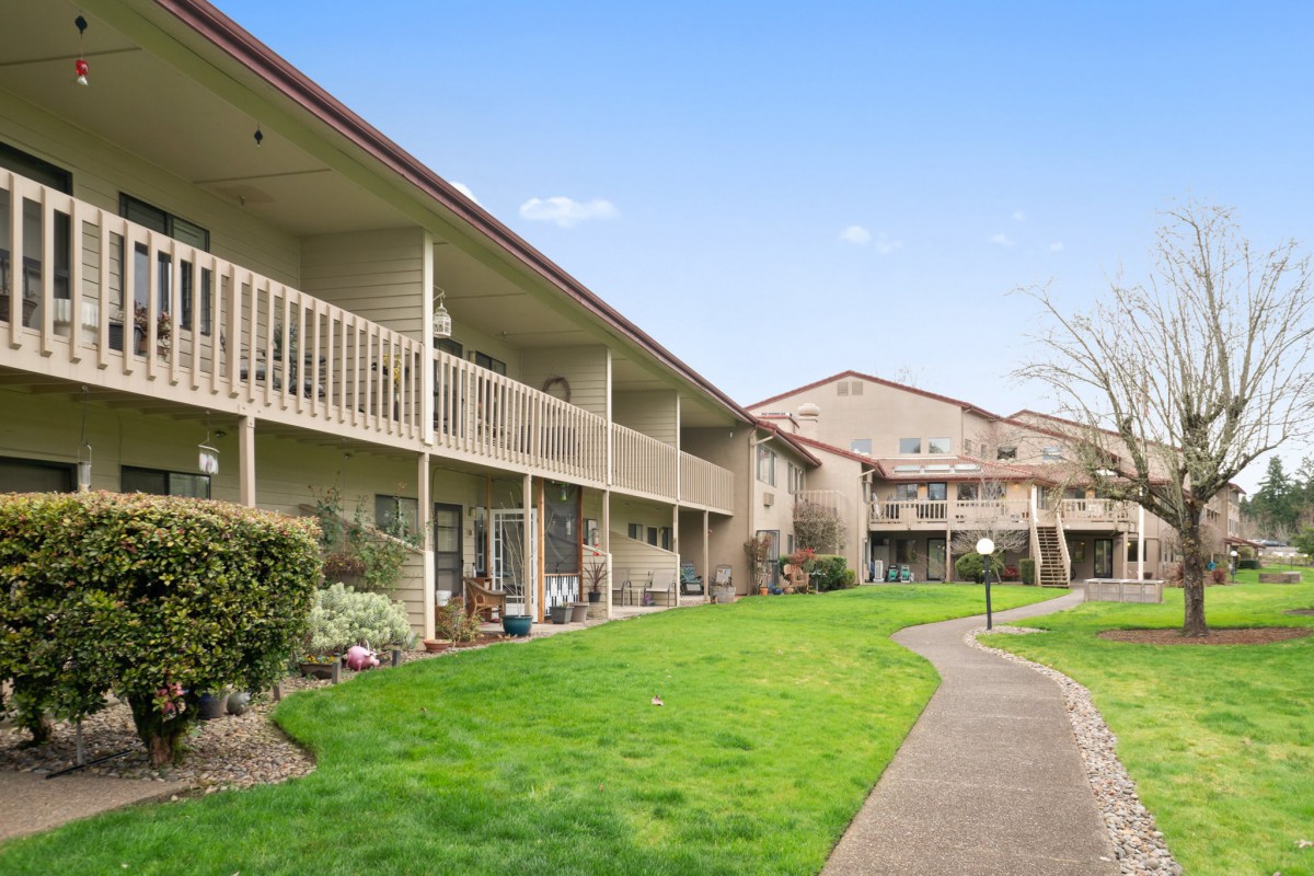 A well-maintained two-story apartment complex with balconies and a lush green lawn.
