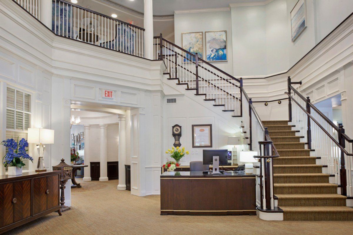 A spacious hotel lobby featuring a reception desk and elegant staircase.