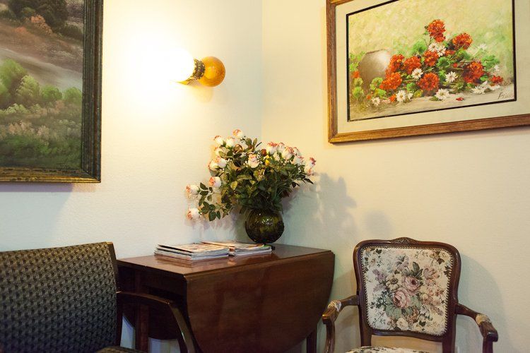 A cozy interior features vintage furniture, floral decor, and wall art.