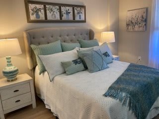 A cozy bedroom with a neatly made bed, featuring multiple pillows and teal accents.
