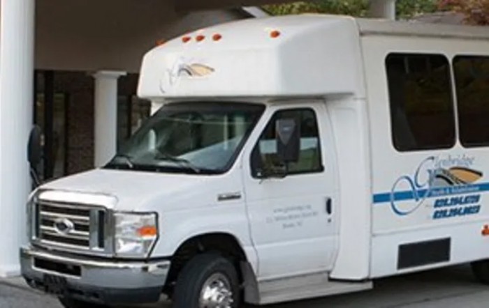 A white shuttle bus parked under a sheltered area.