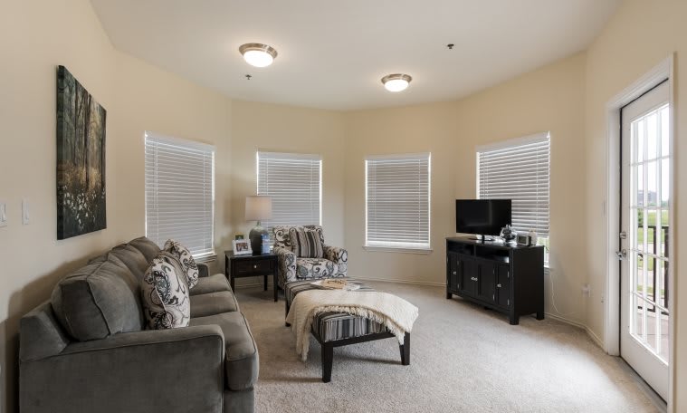 A cozy living room with modern furnishings, featuring a sofa, armchair, and a television.