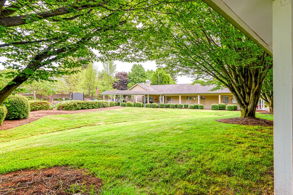 A serene residential home with a well-maintained lawn and surrounding trees.