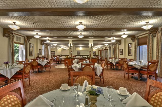 A spacious and elegantly decorated restaurant dining room with neatly arranged tables and chairs.