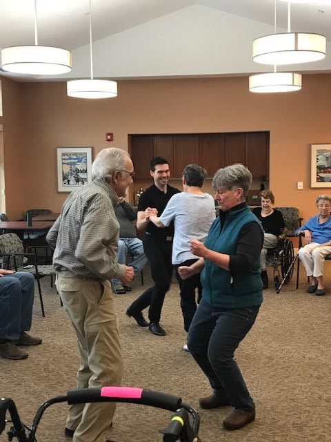 A group of seniors enjoying a dance in a community room.