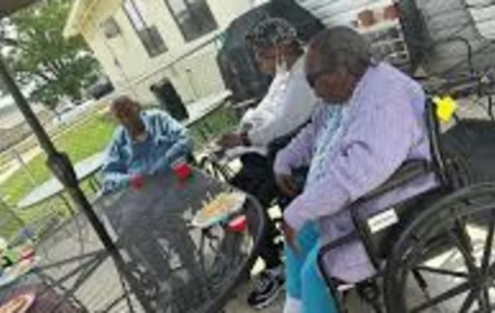 A group of people sitting outside at a table, engaged in conversation.