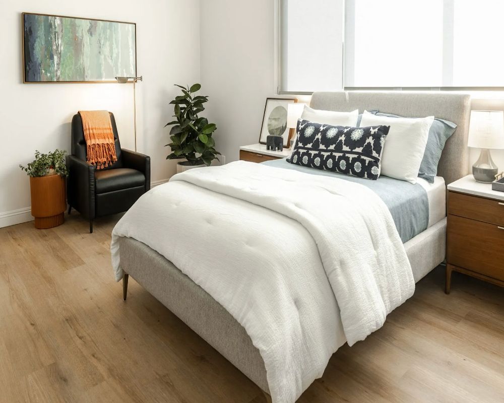 A modern bedroom with stylish decor, featuring a comfortable bed, decorative pillows, and a cozy chair.