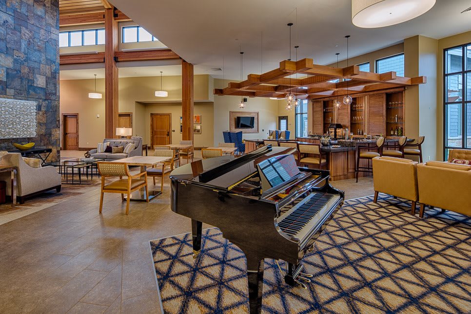 A modern lounge interior featuring a grand piano surrounded by comfortable seating and stylish lighting.