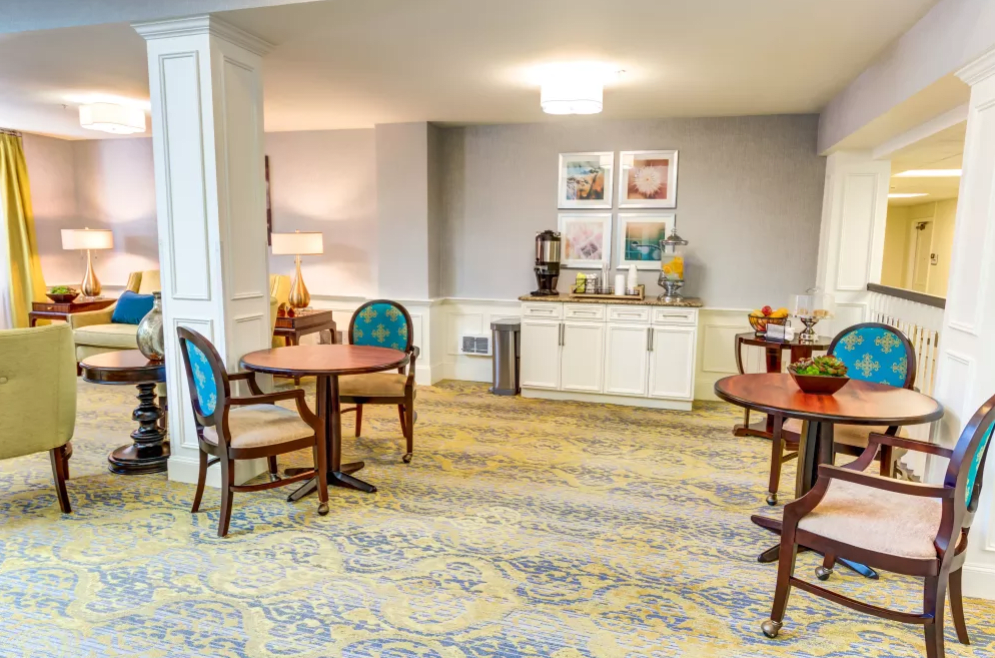A cozy lobby area with tables, chairs, and a coffee station.
