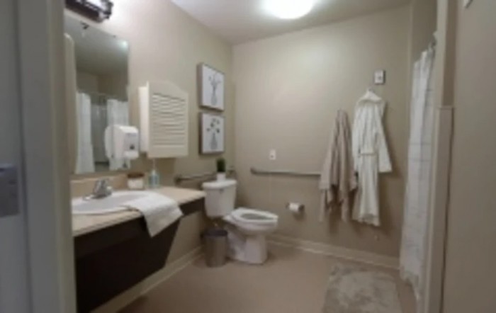 A modern bathroom with a sink, toilet, and hanging robes.