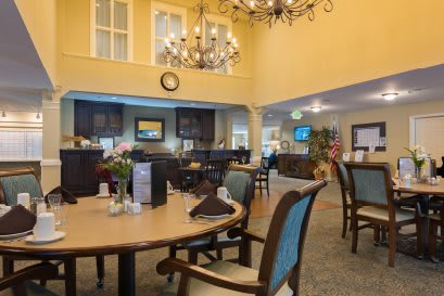 A cozy dining area with elegant chandeliers and neatly arranged tables and chairs.