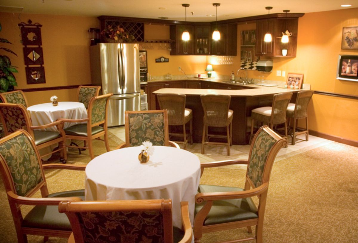 A cozy dining area with a round table and chairs, adjacent to a kitchen featuring a bar counter and stainless steel refrigerator.