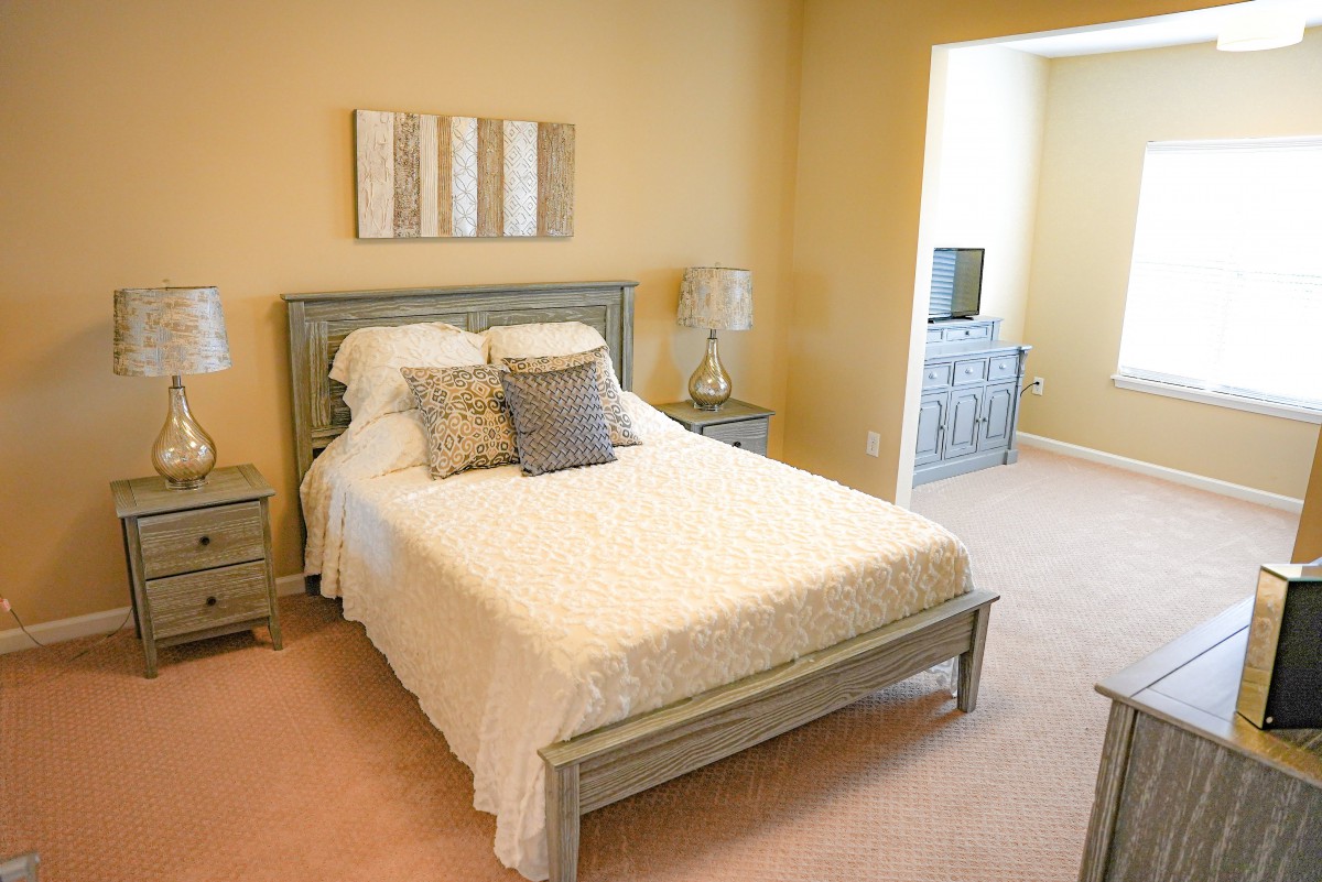 A cozy bedroom with a neatly made bed, pillows, and nightstands on either side.