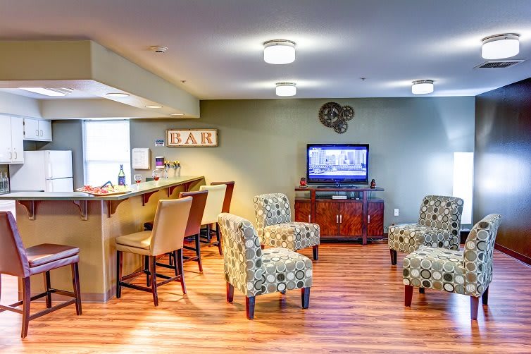 A cozy living space with a bar area and comfortable seating, featuring a television mounted on the wall.