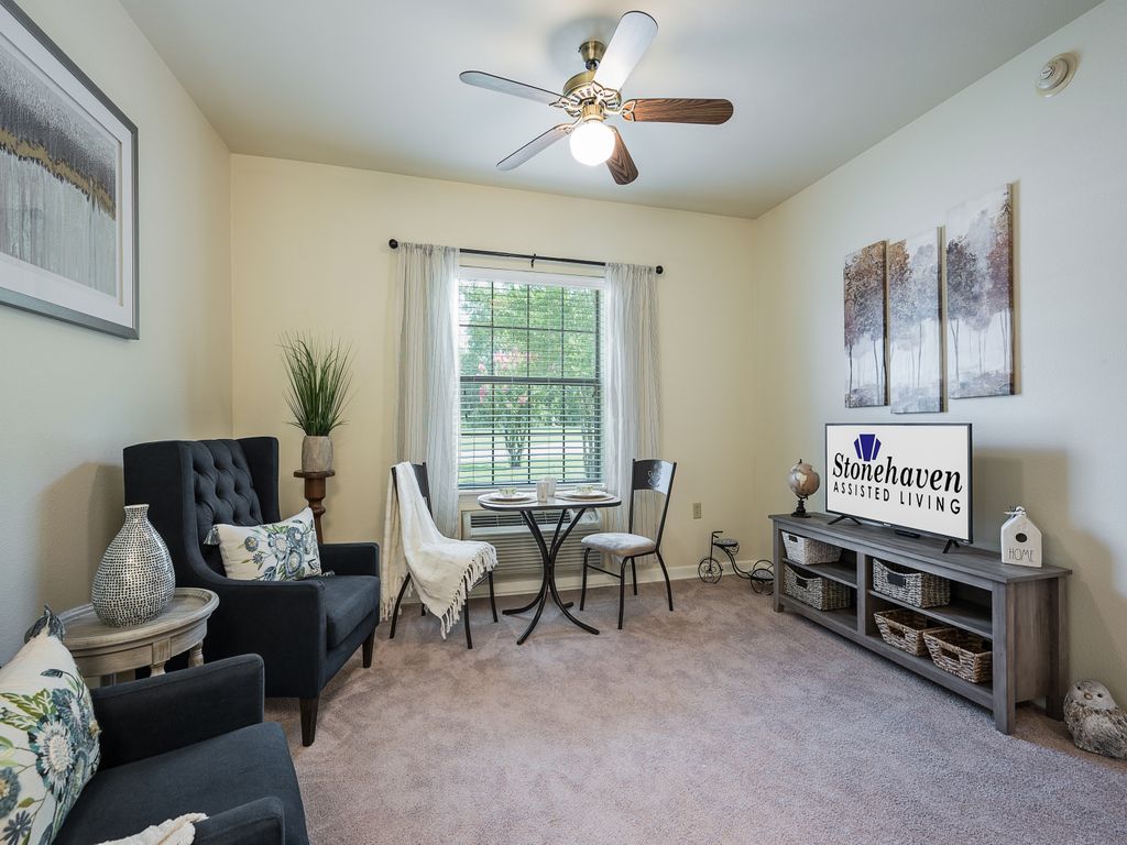A cozy living room with a small dining set, comfortable seating, and a TV stand.