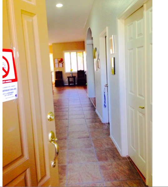 A well-lit corridor in a home with tiled flooring and multiple doors.