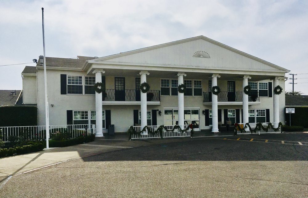 A large white building with columns and festive wreaths on the facade.