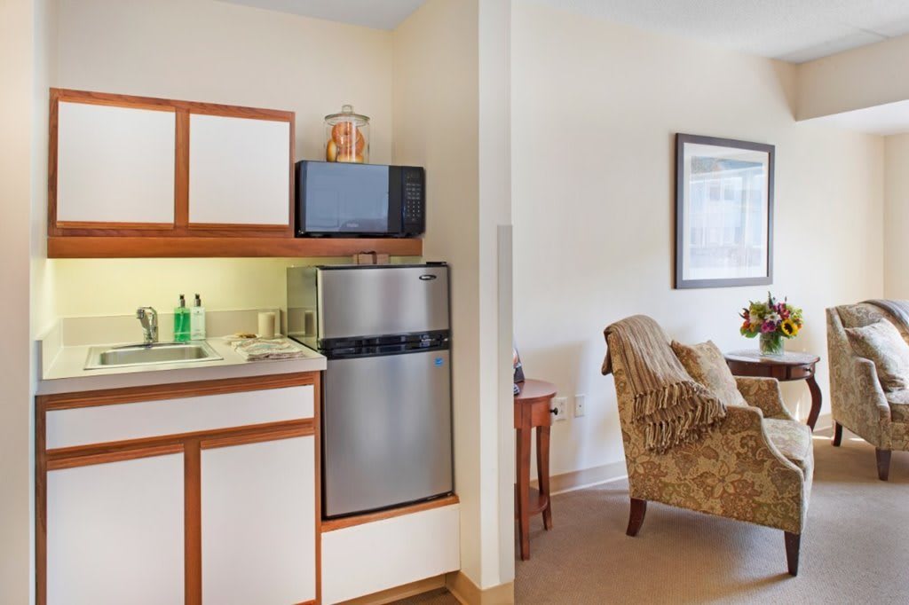 A cozy kitchenette with a microwave, fridge, and sink, adjacent to a comfortable living area.