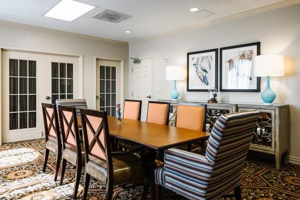 A well-decorated conference room with a large wooden table surrounded by chairs, featuring modern artwork and ambient lighting.