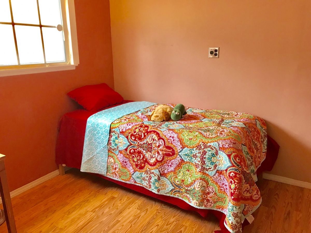 A cozy bedroom with a single bed adorned with a colorful quilt.