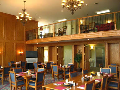 A spacious dining area with elegant chandeliers and neatly arranged tables and chairs.