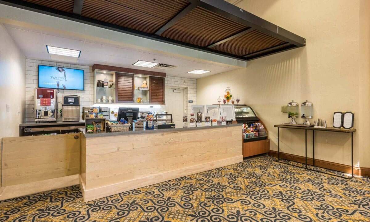 The image shows a hotel reception area with a wooden counter and carpeted floor.