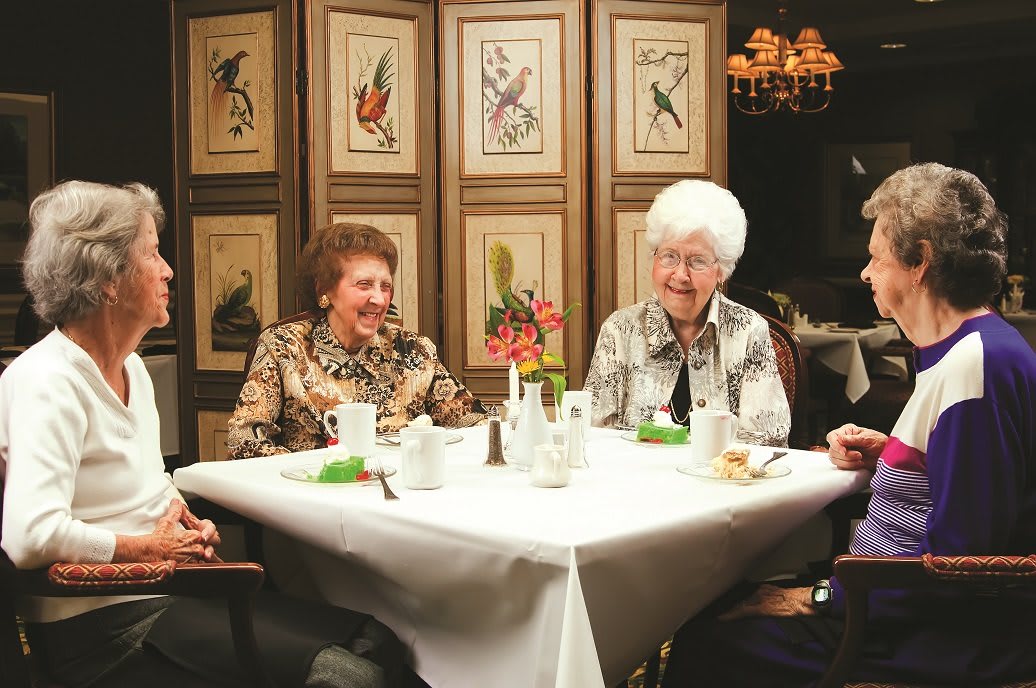 A group of elderly people enjoying a meal and conversation at a restaurant.