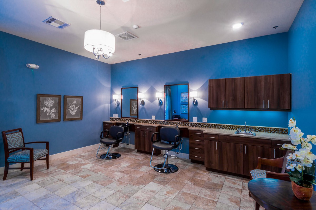 A stylish salon interior with blue walls, mirrors, and comfortable seating.