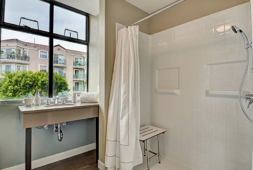 A modern and minimalist bathroom featuring a shower with a curtain, a window with a view, and a sleek sink.