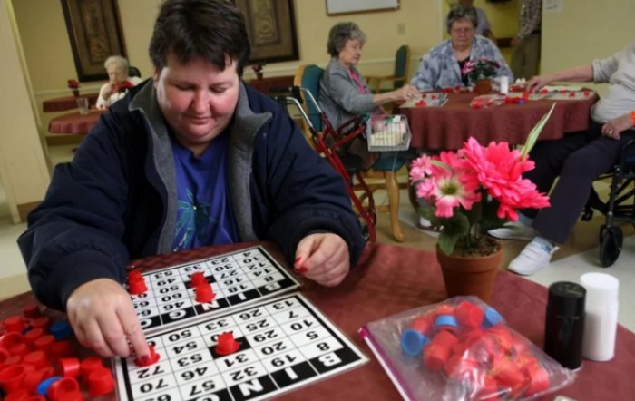 A person playing bingo at a table with flowers and bingo markers.