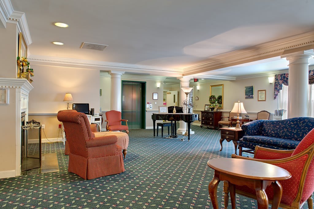 A spacious and well-furnished living room featuring comfortable seating, a piano, and elegant decor.