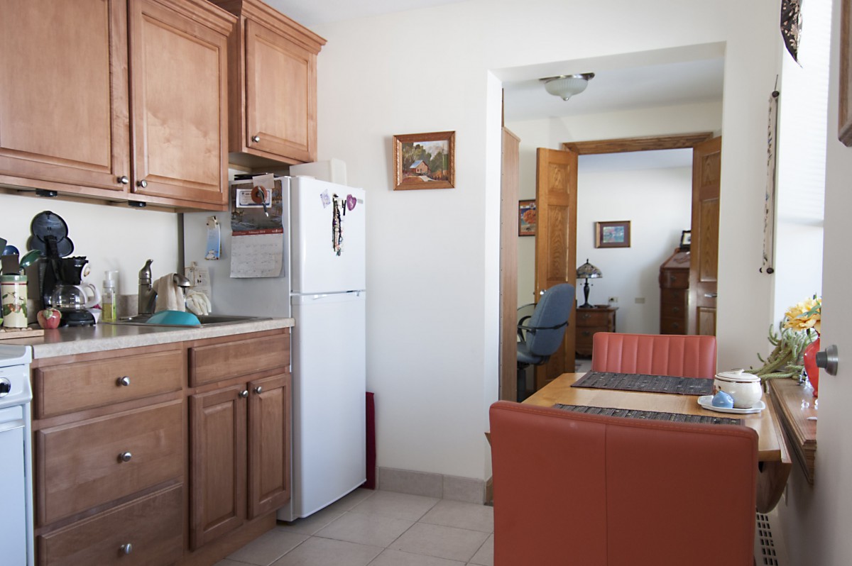 Cozy kitchen and living area featuring wooden cabinets and a white refrigerator.