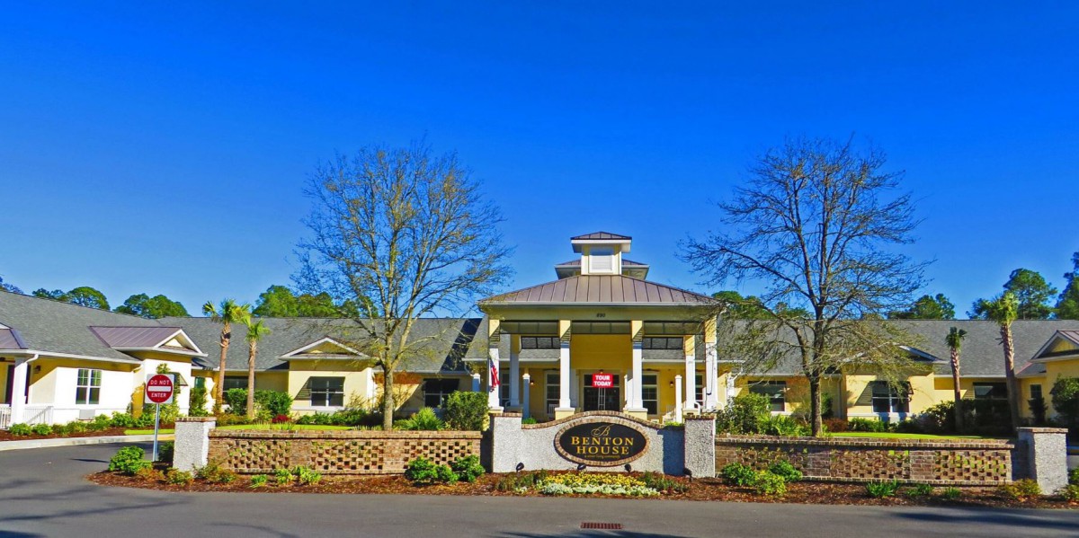 A picturesque building entrance surrounded by lush landscaping and clear blue skies.